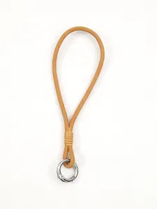 Close-up of handmade camel brown leather phone wrist strap with silver spring clasp