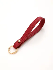 Detail view of a bright red textured leather keychain strap with a gold metal ring