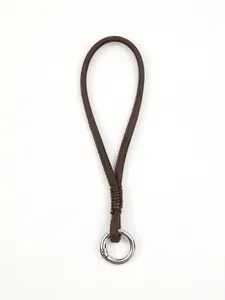 Detailed close-up of a handmade brown leather phone wrist strap with a silver metal spring ring
