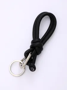 Close-up detail of a minimalist black knotted PU leather phone lanyard with metal ring