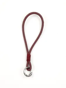 Macro view of handmade burgundy leather phone wrist strap with silver spring ring buckle