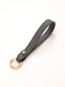 Detailed view of a textured grey leather wristlet strap featuring elegant gold hardware.