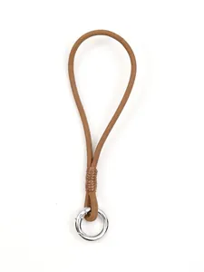 Detail of handcrafted brown leather phone wrist strap with silver metal ring clasp.