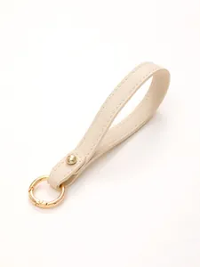 Detailed view of cream pebbled leather keychain wrist strap with gold snap ring