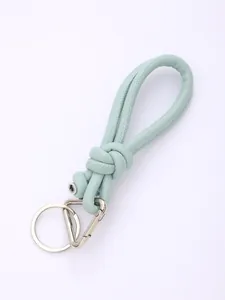 Detail view of light green handmade PU leather knotted keychain with silver metal rings.