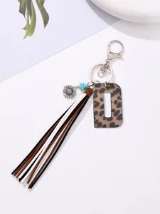 Detail shot of Western-style leopard print letter D keychain with boho tassel and sunflower charm.