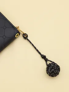 Detailed macro view of a handmade black and white monkey fist knot tassel on a black bag