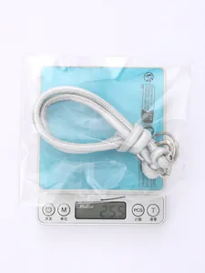 Detail view of silver hand-woven PU lanyard keychain being weighed at 25.5g on a scale.
