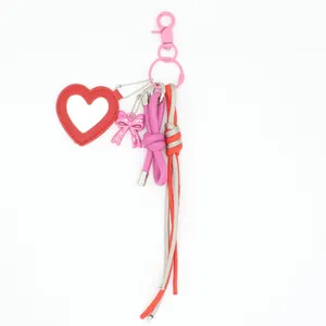 Handmade red heart leather mirror keychain with pink bow and braided rope bag charm.