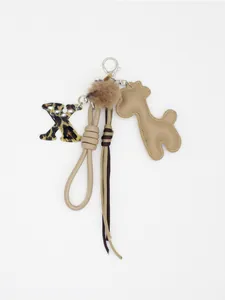 Dettaglio del portachiavi stile Maillard con X leopardata, giraffa in PU e pompon.