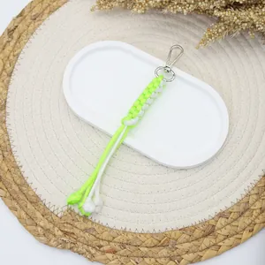 Handmade paracord keychain with fluorescent green and white corn knot on a white tray