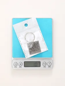 Square leather embossed zinc alloy keychain with letter M weighing 10.7 grams on a scale