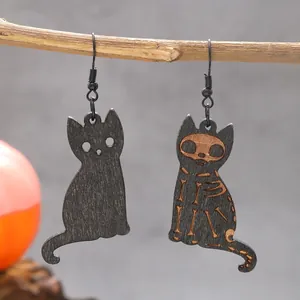 Detailed macro view of spooky Halloween wooden cat skeleton dangle earrings on a branch