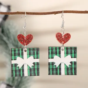 Nahaufnahme von weihnachtlichen Holzohrringen mit rotem Glitzerherz und grünem Karo