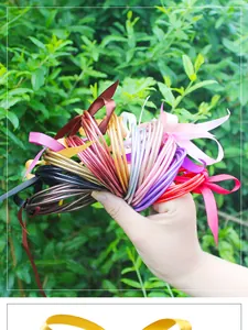 Detailed view of colorful glitter jelly bangles with satin ribbons held by hand.