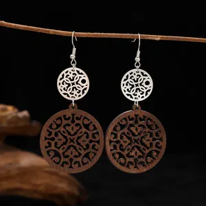 Detailed view of vintage wooden and silver filigree drop earrings hanging on a twig