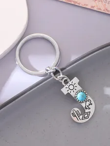 Close-up of silver-tone letter J keychain with turquoise stone and desert engraving detail.