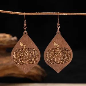 Macro view of wooden teardrop earrings featuring engraved leopard pumpkin detail.
