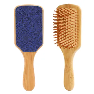 Detailed view of a vintage style bamboo hairbrush featuring an embossed blue floral leather back.