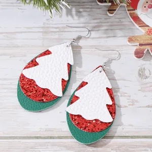 Nahaufnahme festlicher Tropfenohrringe mit einem Weihnachtsbaummuster aus Leder.