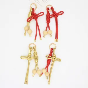 Detalle de cerca de llaveros de nudo chino trenzados a mano en cuero sintético rojo y dorado.