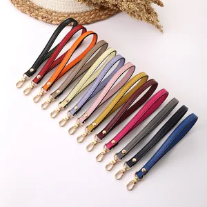 Detailed macro view showing a variety of colorful leather wristlet straps with gold-tone keychains
