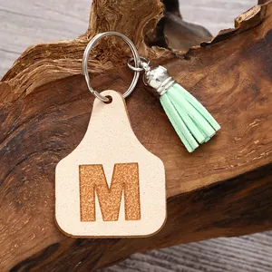 Detailed view of a mint green tassel keychain with an embossed leather letter M charm.