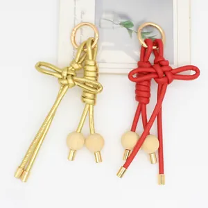 Detalle de colgantes de bolso de cuero PU trenzado rojo y dorado con cuentas de madera.