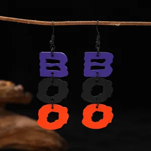 Close-up of Halloween BOO wooden dangle earrings with purple black and orange colors