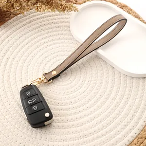 Close-up of a minimalist khaki leather wristlet strap with a gold-tone keychain clasp.