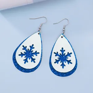 Nahaufnahme der blauen Glitzer- und weißen Leder-Schneeflockenohrringe für Weihnachten
