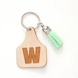 Minimalist farm-style leather tag keychain with engraved letter W and green tassel detail
