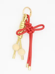 Detalle de un llavero de nudo chino tejido a mano en rojo y dorado con cuentas de madera