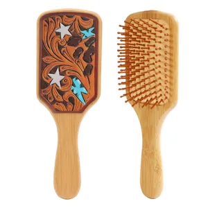 Detail view of bamboo hairbrush with western cowboy leather tooling and cow print patterns.