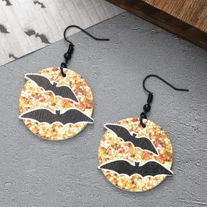 Close-up of wooden Halloween drop earrings featuring black bat patterns on orange glitter.