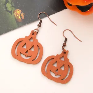 Detail view of Halloween pumpkin wooden drop earrings with classic jack-o'-lantern face