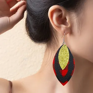 Close-up detail of multi-layered leaf earrings with red plaid and gold glitter