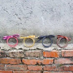 Set of five gold foil silicone jelly bangles with decorative silk ribbons for women.