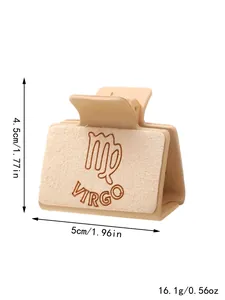 Detailopname van beige haarklem met lasergegraveerd Maagd-symbool en suède-achtige textuur