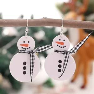 Nahaufnahme von weißen Leder-Schneemann-Ohrringen mit schwarz-weiß karierten Schals an einem Ast.
