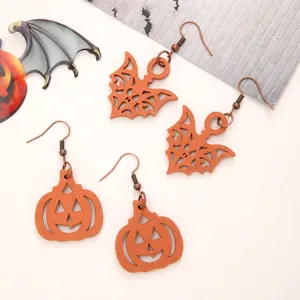Detail view of Halloween wooden dangle earrings with orange pumpkin and bat shapes.