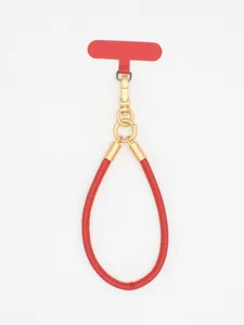Macro view of stylish red PU leather phone wrist strap featuring a golden metal buckle