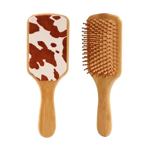 Natural bamboo paddle hairbrush featuring a stylish cow print leather backing