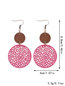 Vista dettagliata di orecchini rotondi in pelle traforata rosa con accenti in legno
