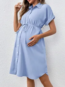 Close-up of light blue maternity shirt dress with drawstring waist and button detail