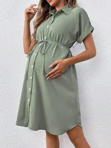 Close-up of sage green maternity shirt dress featuring functional buttons and waist tie