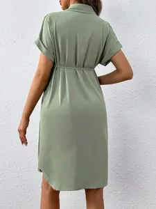 Back view of a sage green maternity shirt dress with short sleeves and tie waist