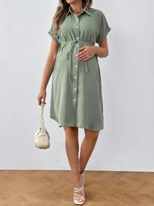 Sage green short-sleeved maternity shirt dress with a waist tie detail.