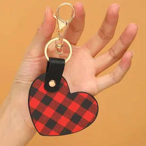 Herzförmiger Leder-Schlüsselanhänger mit rot-schwarzem Karomuster und Goldring.