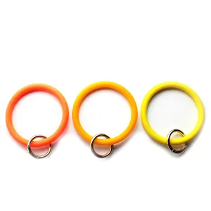Tre portachiavi da polso in silicone colorato con fermagli in metallo dorato su bianco.